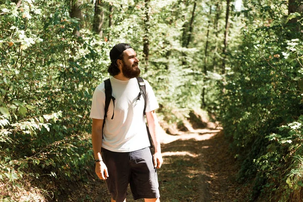 Foto de um jovem homem barbudo caminhando na floresta durante o verão, — Fotografia de Stock