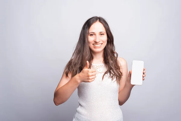 Retrato de jovem mulher feliz mostrando polegar para cima e branco vazio tela móvel — Fotografia de Stock