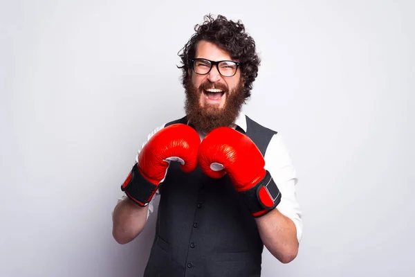 Portrét mladého vousatého muže v obleku křičící a boxující s boxerskými rukavicemi — Stock fotografie