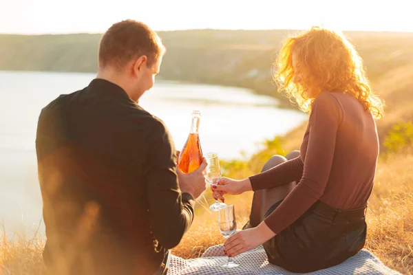 A young couple having a picnic serving champagne in the field — Stock Photo, Image