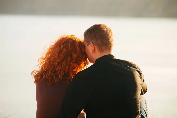 Una joven pareja agradable sentados uno al lado del otro teniendo un tiempo juntos cerca de un río —  Fotos de Stock