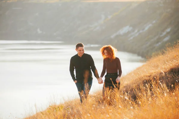 Foto de pareja feliz disfrutando del tiempo juntos y caminando en los campos durante el atardecer —  Fotos de Stock