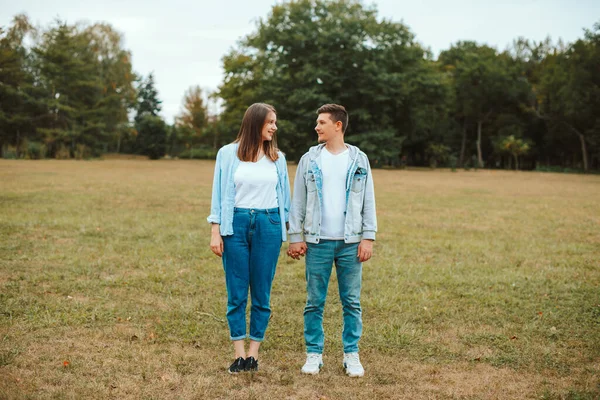 Photo of young family standing in park holding hands and looking at each other — Stock Photo, Image