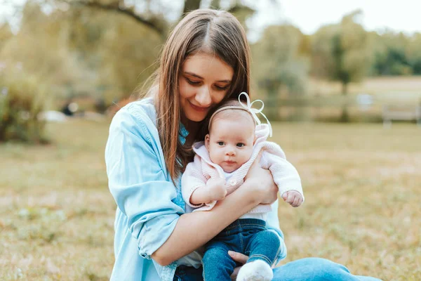 Photo of young lovely mother sitting outdoor with her little baby girl — Stock Photo, Image