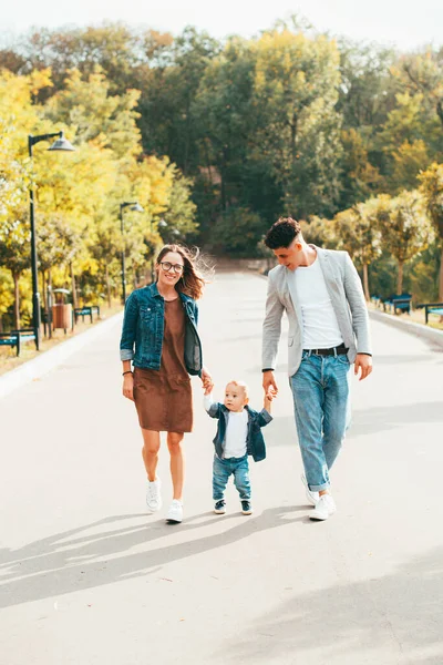 Young family with a baby walking through the park — Stock Photo, Image