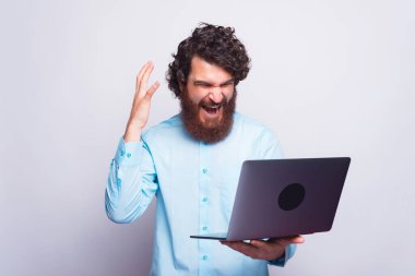 Mavi gömlekli kızgın adam işte sorun yaşıyor, adam dizüstü bilgisayara bağırıyor.