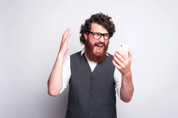 Hombre frustrado y enojado mirando el teléfono inteligente y gritando, malas noticias — Foto de Stock