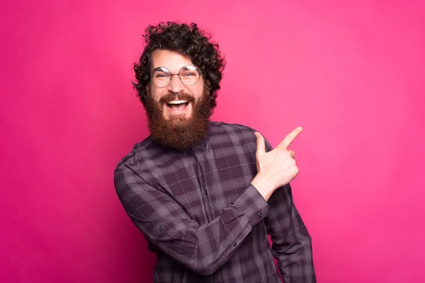 Een jonge vrolijke bebaarde man met een bril stampt weg en glimlacht naar de camera — Stockfoto