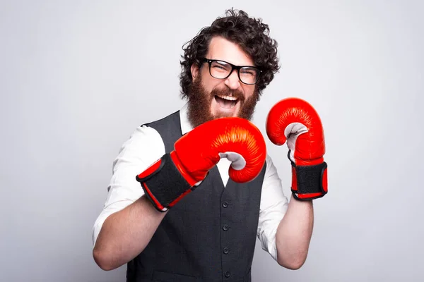 Vousatý mladý a šťastný muž s brýlemi a boxerskými rukavicemi křičí a dívá se do kamery — Stock fotografie