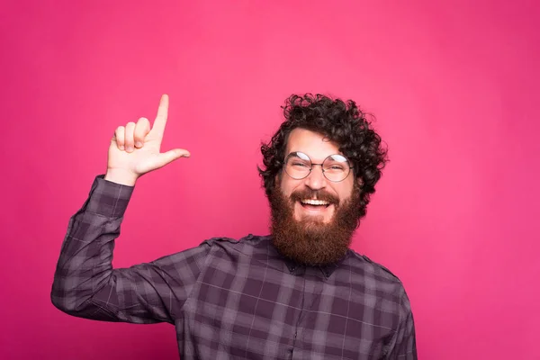 Izgatott, fiatal, szemüveges szakállas férfi egy szabad helyre mutat, és mosolyog a kamerába. — Stock Fotó