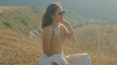 Güzel bir manzarada doğanın tadını çıkaran, huzur ve stil saçan bir kadının huzurlu anı..