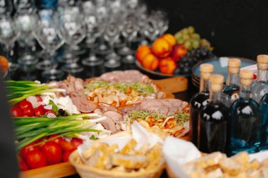 Güzel düzenlenmiş bir yemek masasında çeşitli aperatifler, taze meyveler ve zarif cam eşyalar sergilenir.