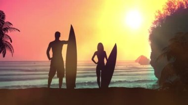 Okyanusta günbatımının arka planında sörfçülerin siluetleri.