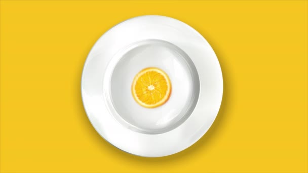 Naranja sobre un plato blanco sobre un fondo amarillo. — Vídeos de Stock