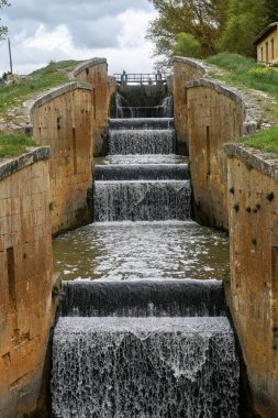 Fromista, Palencia 'daki Castilla Kanalı' nda akan su ile dört basamaklı eski bir taş kilit.