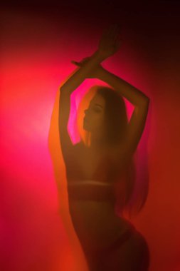 Bir kız iç çamaşırı giyen mor ve turuncu renk ışık silüeti mat camdan ateş