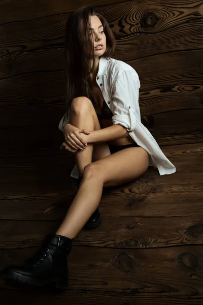 美しいブルネットの少女インテリアを着て黒いランジェリー 特大の白いシャツ 黒いブーツの官能的な肖像画 — ストック写真