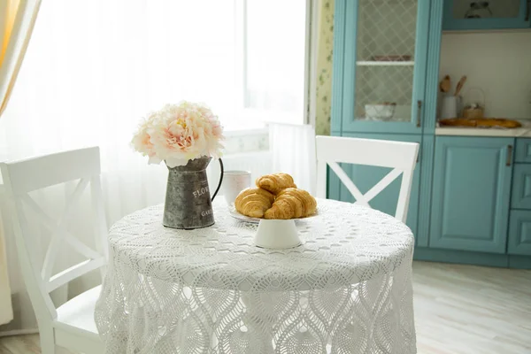 Food and flowers on a kitchen table in the morning. Concept of comfort, hospitality and cosiness.