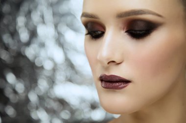 Parlak Metalik arka planda stüdyoda makyaj giyen genç çekici kız güzellik portresi