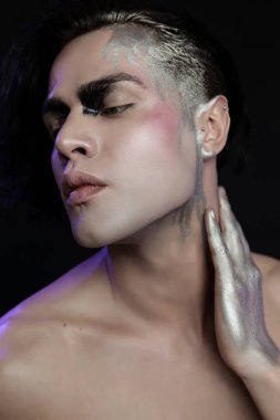 Yüz sanatıyla, menekşe ışığıyla güzel bir genç adamın stüdyo portresini kapat..