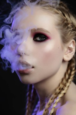 Smoky eyes, tender, violet light ile güzel genç kız stüdyo portresi kapatın. Sigara içme konsepti.