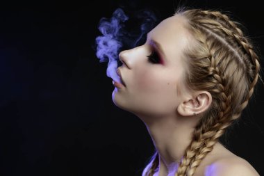 Smoky eyes, tender, violet light ile güzel genç kız stüdyo portresi kapatın. Sigara içme konsepti.