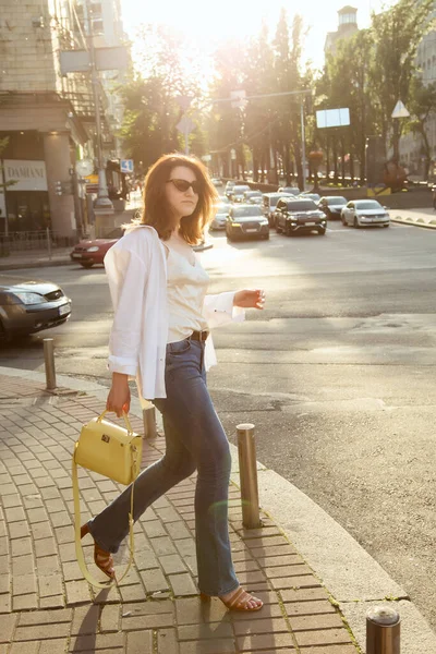 Güzel esmer bir kadının açık hava portresi, şık bir sokak fotoğrafı yürüyüşü, sokak modası