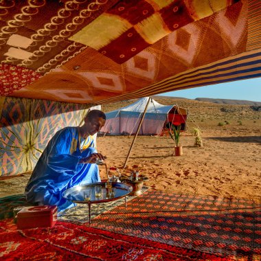 : Guelmim, Morocco - 30 Ekim 2015: Guelmim Sahra Çölü, Fas içinde yakınlarında kamp konukları için çay hazırlama Berber adam.