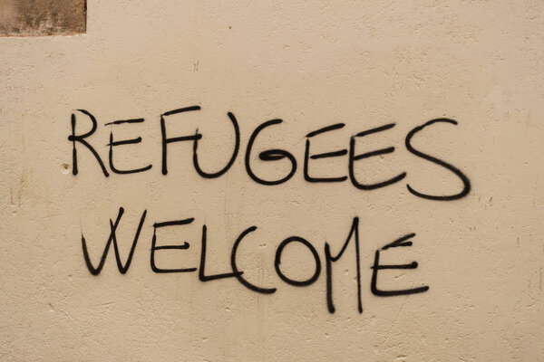 Graffiti with political slogan "Refugees Welcome" on wall