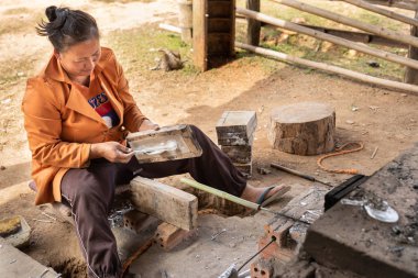 Phonsovan, Laos - 29 Ocak 2019: savaş kaşık patlamamış salvaged hurda alüminyum kullanarak yapma kadın ABD gizli savaş sırasında düştü.