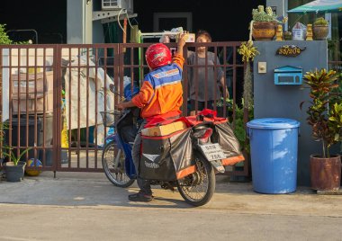 Nisan 2020 'de Bangkok, Tayland' da motosikletli bir postacı posta dağıtıyor..      