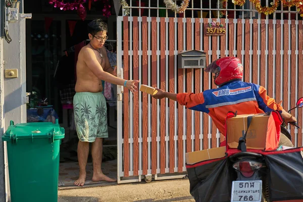 Nisan 2020 'de Bangkok, Tayland' da motosikletli bir postacı posta dağıtıyor..      
