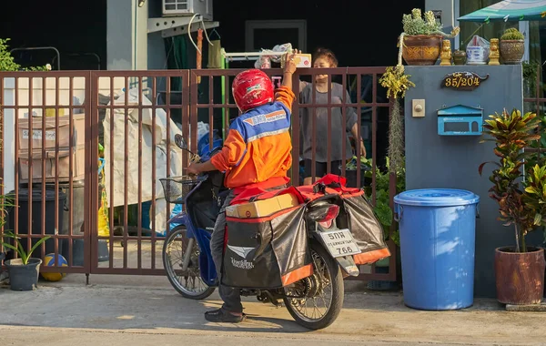 Nisan 2020 'de Bangkok, Tayland' da motosikletli bir postacı posta dağıtıyor..      