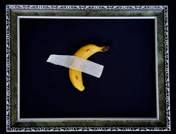 Duvarında bir parça koli bandı olan bir muz, resim çerçevesinde..