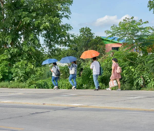  Haziran 2020 'de Pathumthani, Tayland' da kırsal bir yolda yürüyen şemsiyeli insanlar.                                