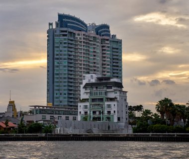 2019 Ağustos 'unda Bangkok, Tayland' da günbatımında nehir kıyısındaki apartman binaları..                                          