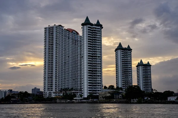 2019 Ağustos 'unda Bangkok, Tayland' da günbatımında nehir kıyısındaki apartman binaları..                                          