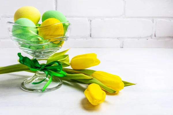 Easter green eggs, yellow tulips, copy space