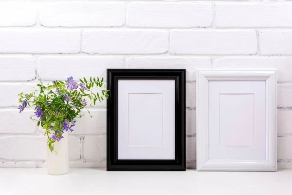 Two black white frames with mat mockup with purple bird vetch in the cylinder vase. Empty poster frame mock up for presentation design. Template framing for modern art.