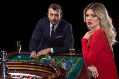 Güzel genç bir kadın ve bir adam bir rulet masasında oturuyor. Casino.