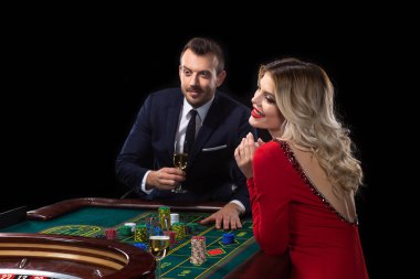Güzel genç bir kadın ve bir adam bir rulet masasında oturuyor. Casino.