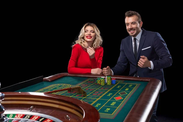 Hermosa y bien vestida pareja jugando ruleta en el casino — Foto de Stock