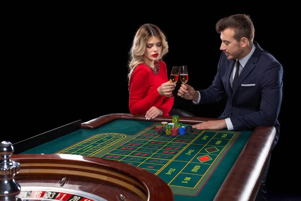 Hermosa y bien vestida pareja jugando ruleta en el casino — Foto de Stock