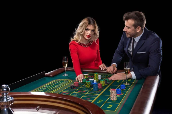 Hermosa y bien vestida pareja jugando ruleta en el casino — Foto de Stock