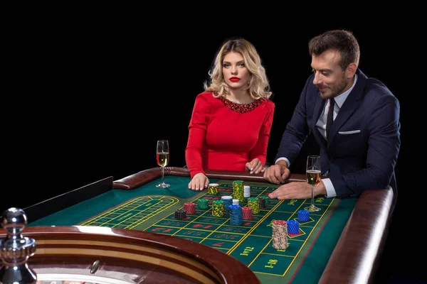 Bella e ben vestita coppia che gioca alla roulette nel casinò — Foto Stock