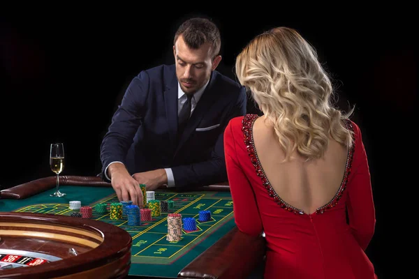 En vacker ung kvinna och en man sitter på ett roulette-bord. Casino. — Stockfoto