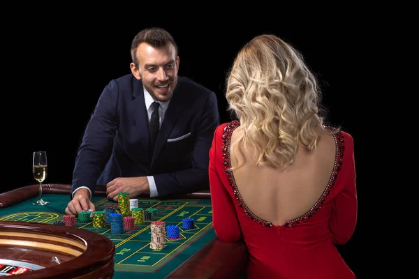 Una hermosa joven y un hombre están sentados en una mesa de ruleta. Casino Casino . — Foto de Stock