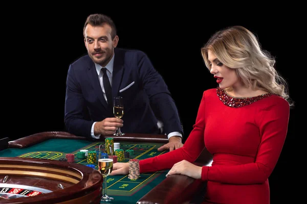 Una hermosa joven y un hombre están sentados en una mesa de ruleta. Casino Casino . — Foto de Stock