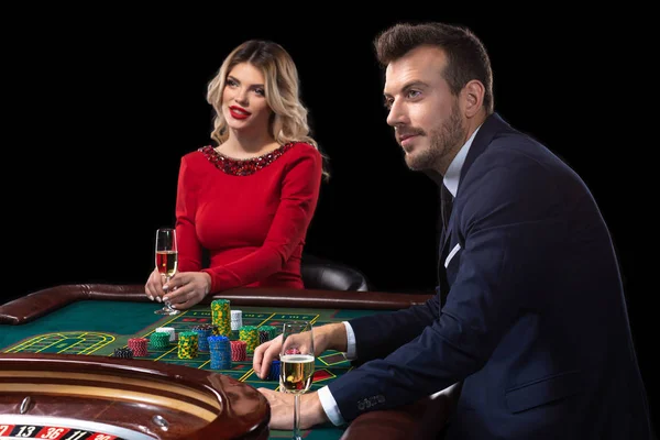 Güzel genç bir kadın ve bir adam bir rulet masasında oturuyor. Casino.