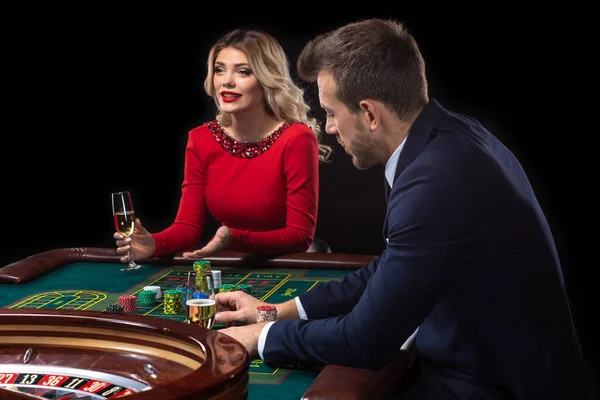 Una hermosa joven y un hombre están sentados en una mesa de ruleta. Casino Casino . — Foto de Stock